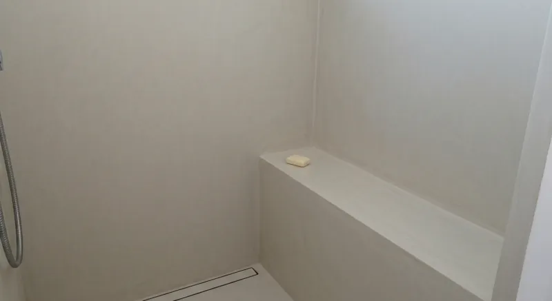 Banco de ducha en microcemento integrado en la pared en Gavà