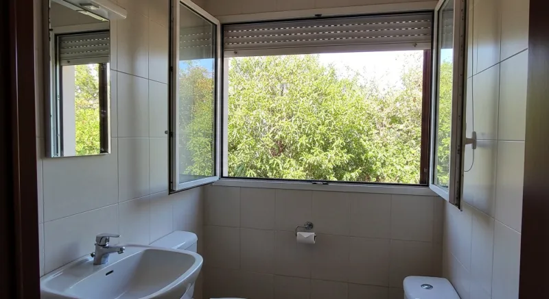 Baño estrecho con microcemento, ventana al jardín en Castelldefels